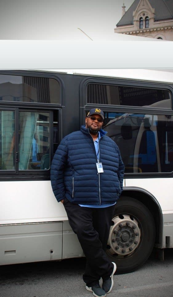 Darnell Barton standing in front of a city bus.